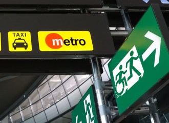 An exit sign with the running person pictogram and another way with an arrow pointing the other way with a wheelchair user and a running person pictogram