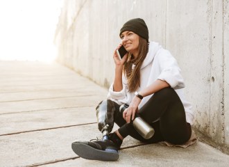 A young fashionable girl sitting on a ramp using the phone, she wears a prosthetic lower leg
